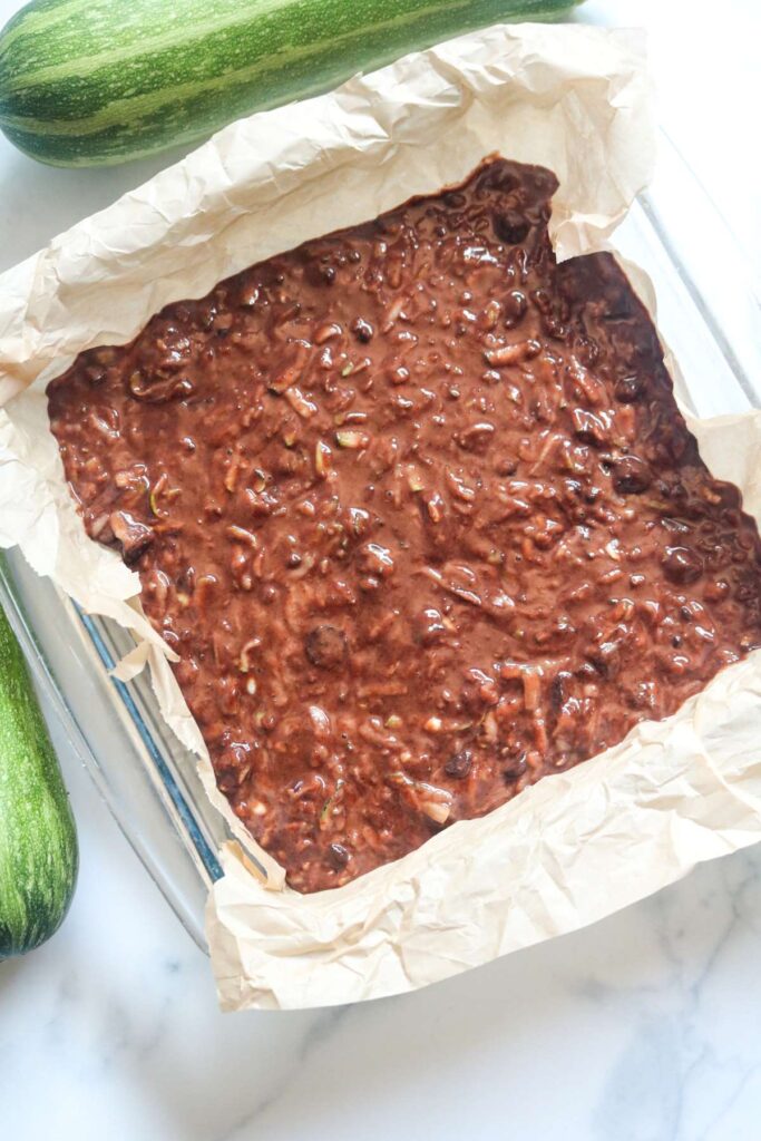 zucchini brownies batter in pan with parchment paper