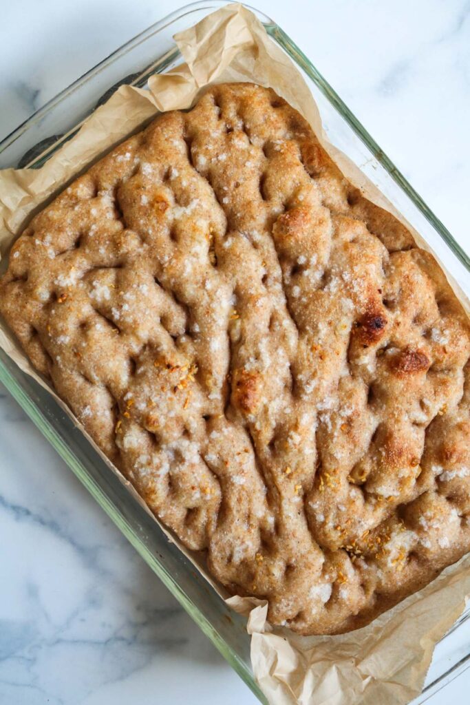 finished focaccia bread in glass baking dish with parchment paper