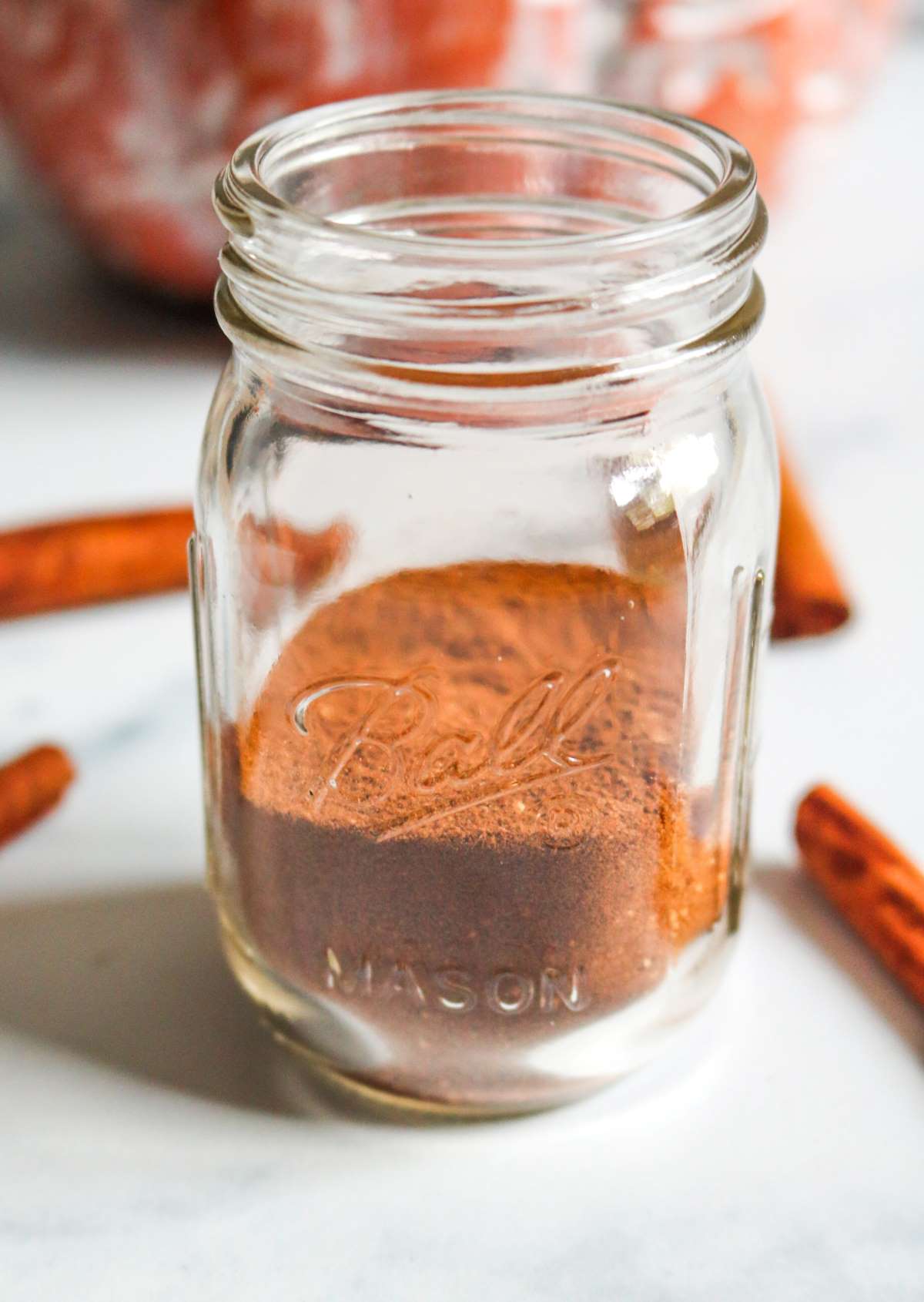 pumpkin pie spice in small mason jar with cinnamon sticks in background