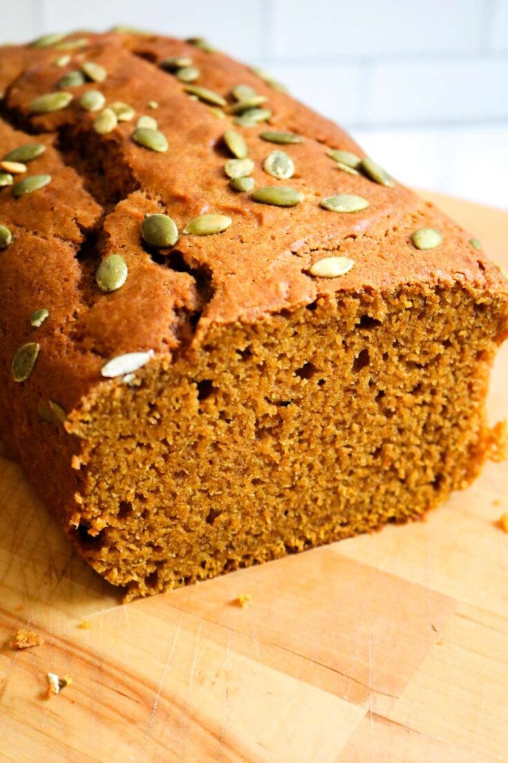 pumpkin bread cut showing inside on wood cutting board