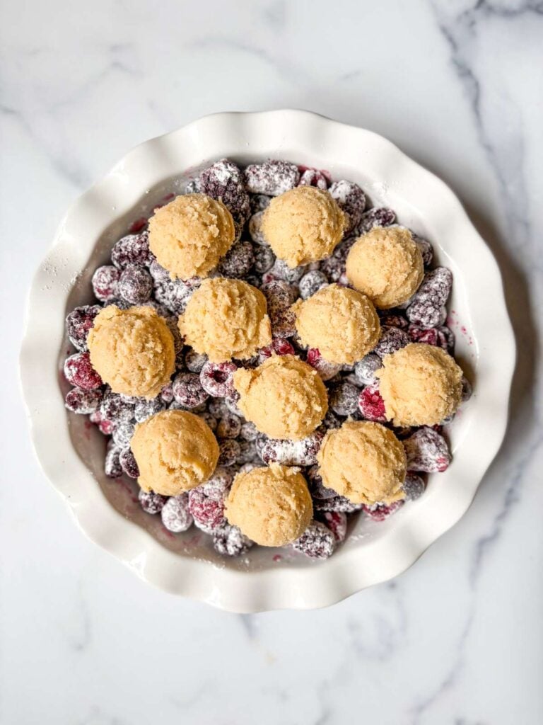 mixed berries in pie dish with lemon sugar cookie dough on top