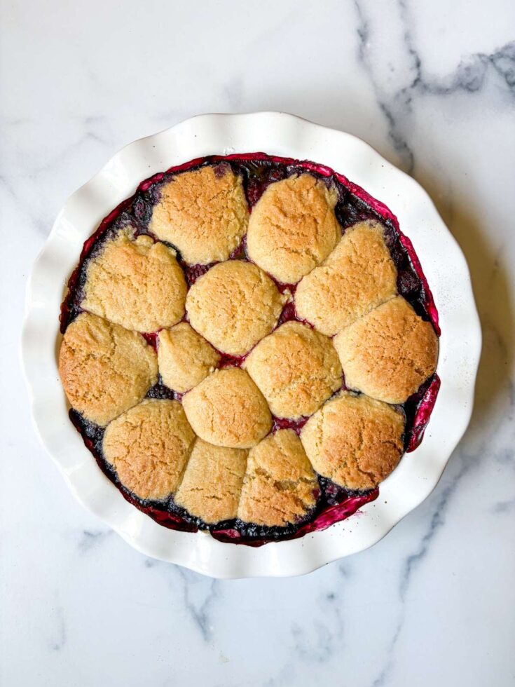 white pie dish with berries and topped with lemon sugar cookies