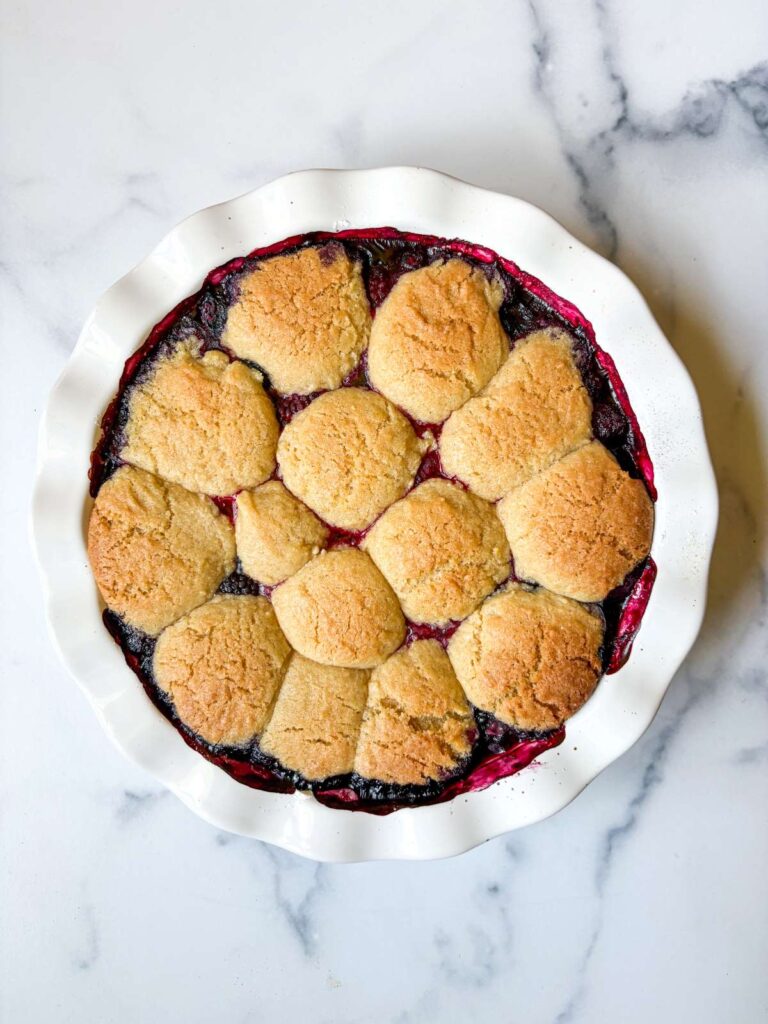 white pie dish with berries and topped with lemon sugar cookies